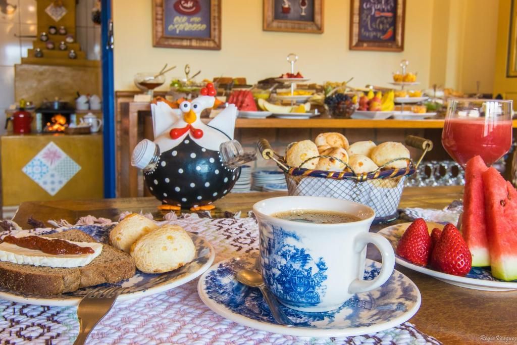 Mesa de café com pão de queijo, frutas e café